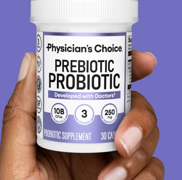 A hand holding a bottle of Physician's Choice Prebiotic Probiotic